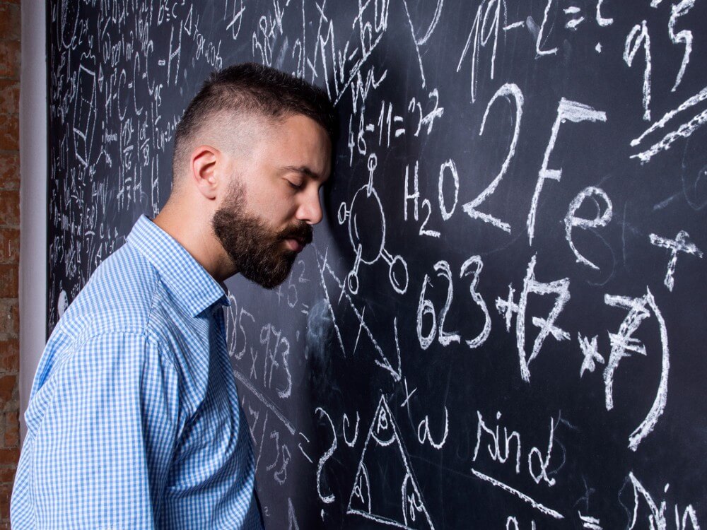 Teacher with eye closed thinking I hate teaching with his head against a chalkboard.