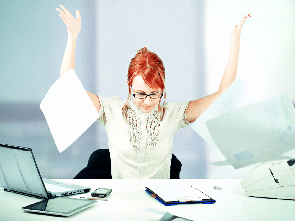 Woman at desk throwing papers into the air.