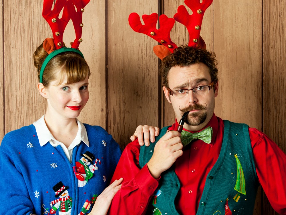 A man and woman dressed in Christmas sweaters.